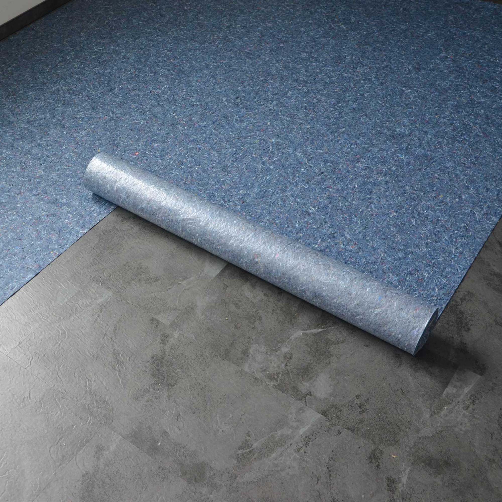 Aufgerolltes blaues Abdeckvlies auf grauem Boden als robuster Schutz für Böden bei Umzug, Renovierung und Malerarbeiten