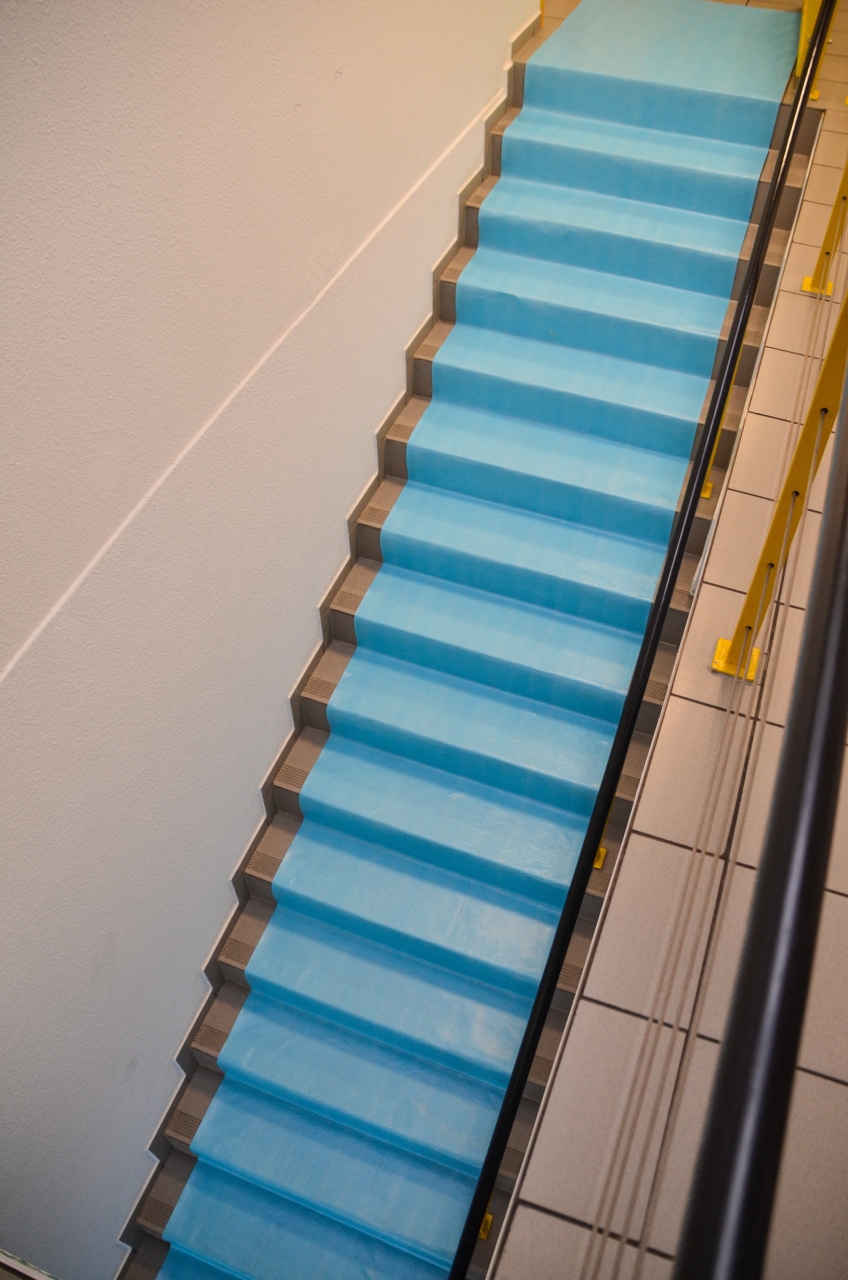 Mit blauer Treppenschutzfolie abgedeckte Innentreppe zum Schutz vor Schmutz und Beschädigungen während Renovierungsarbeiten