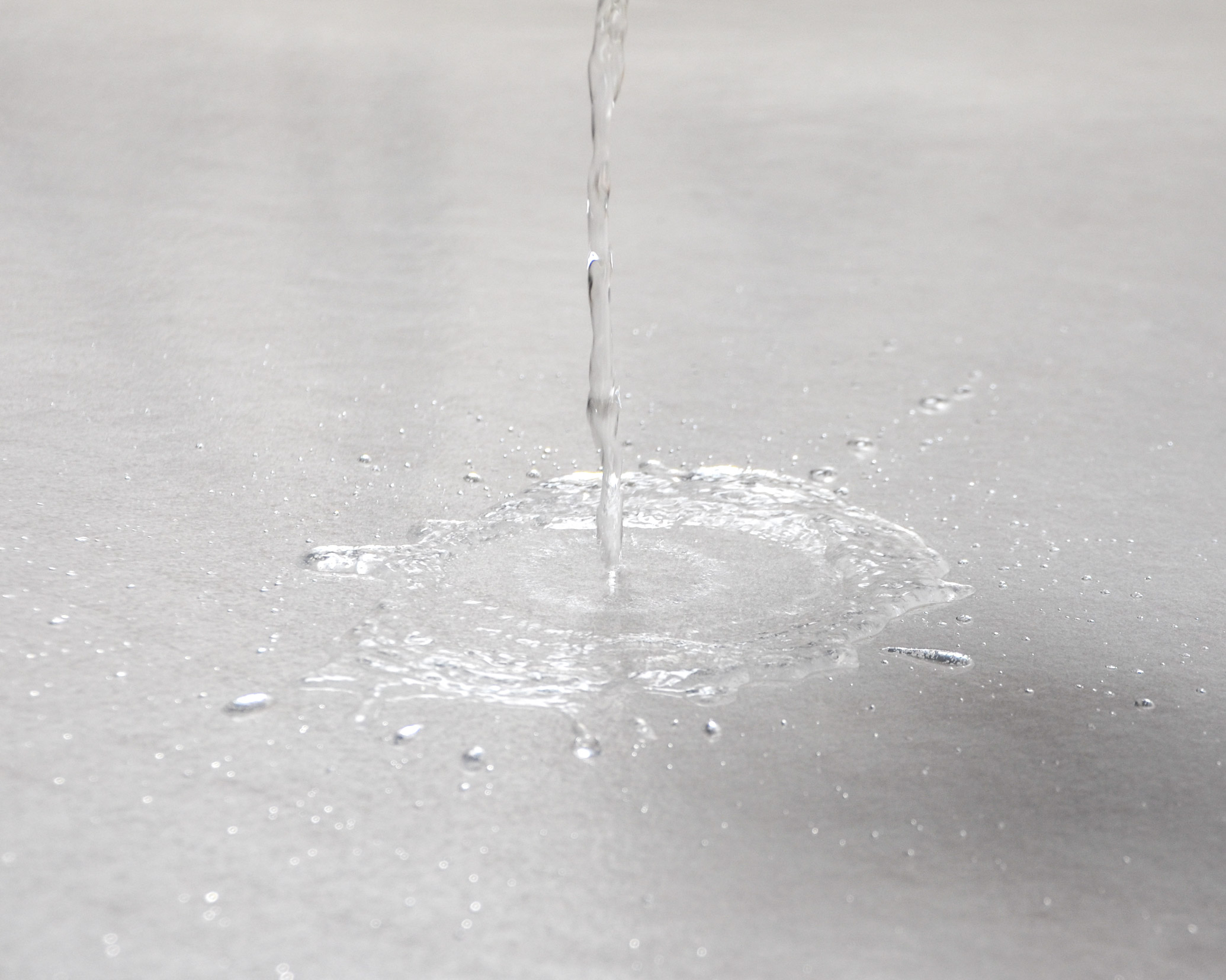 Wasser wird auf das selbsthaftende ZERO DUST TreppTurbo Boden- und Treppenschutzvlies 140 g/m² gegossen – Schutz für Böden, Treppen und Laufwege bei Renovierungsarbeiten.