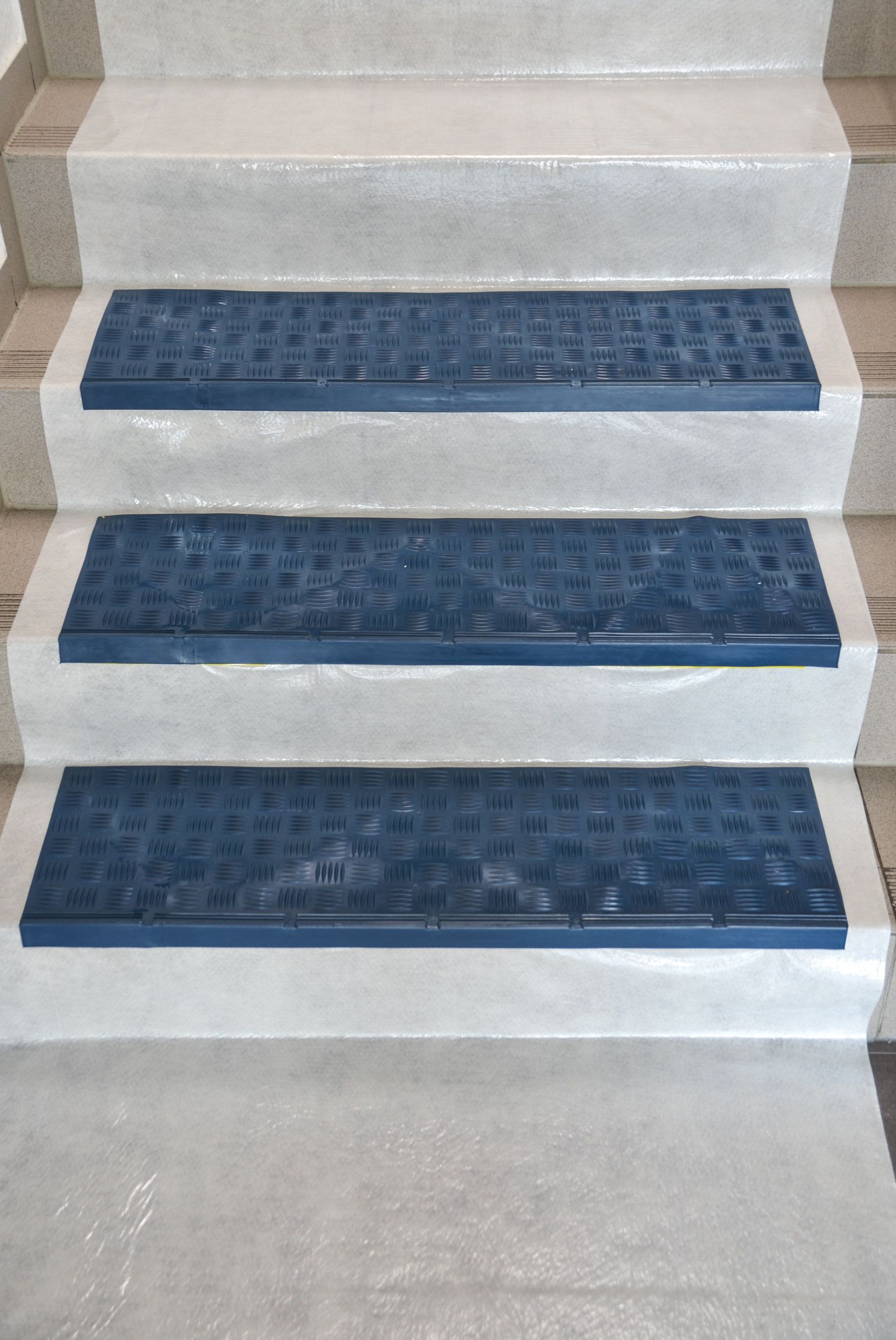 Mehrere blaue, rutschfeste Gummi-Treppenstufenmatten auf hellen Treppenstufen für zusätzlichen Sicherheitsschutz montiert