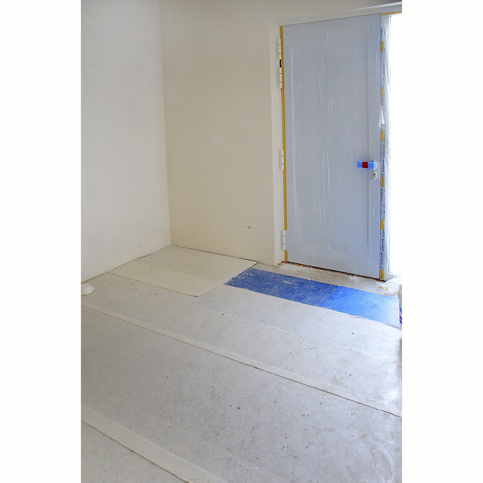 Mit Abdeckfolie geschützter Boden und Türrahmen in einem renovierten Raum, idealer Oberflächenschutz bei Bau- und Malerarbeiten