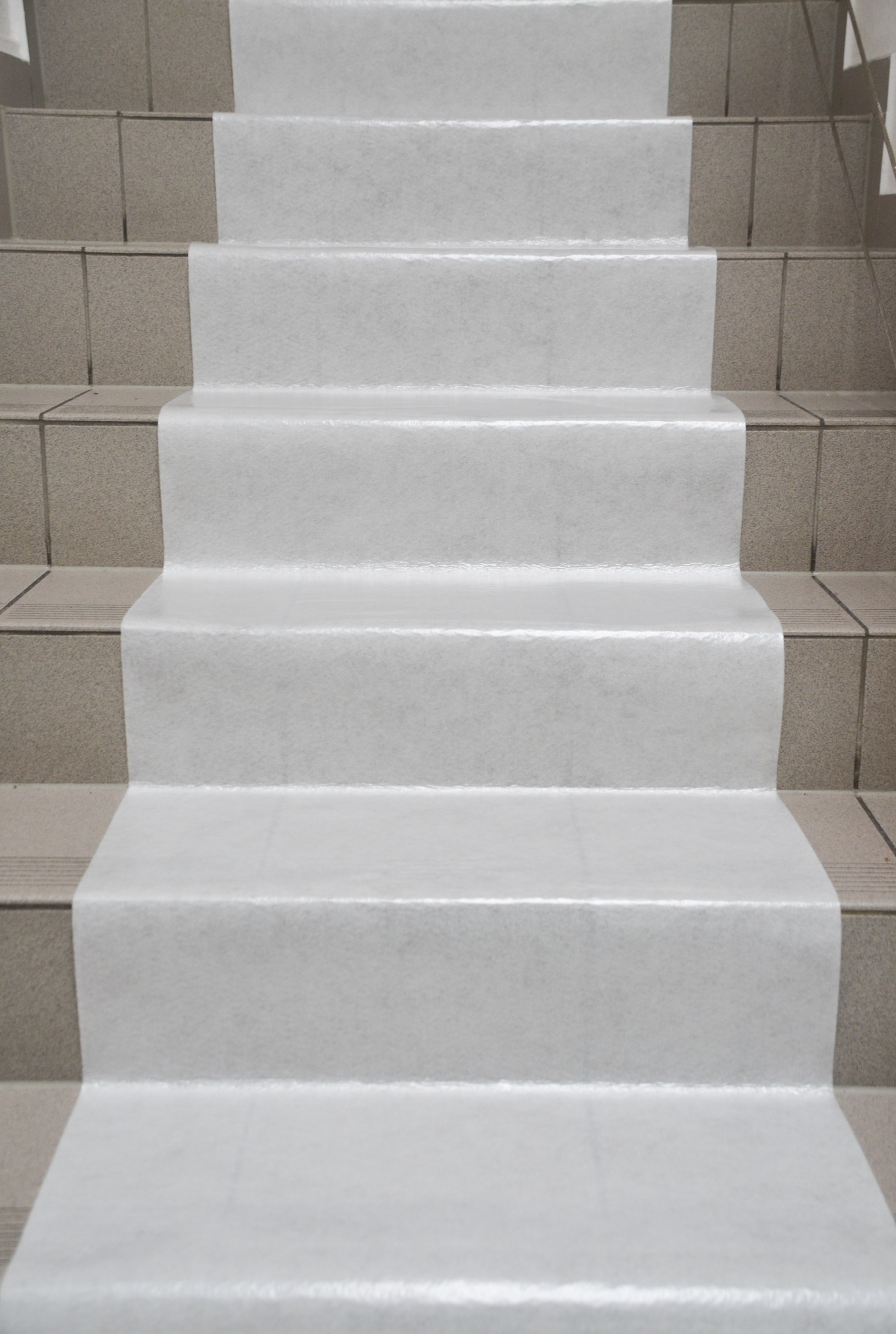 Weiße Treppenschutzfolie als temporärer Abdeckschutz auf gefliester Treppe, rutschfest und widerstandsfähig für Renovierungsarbeiten