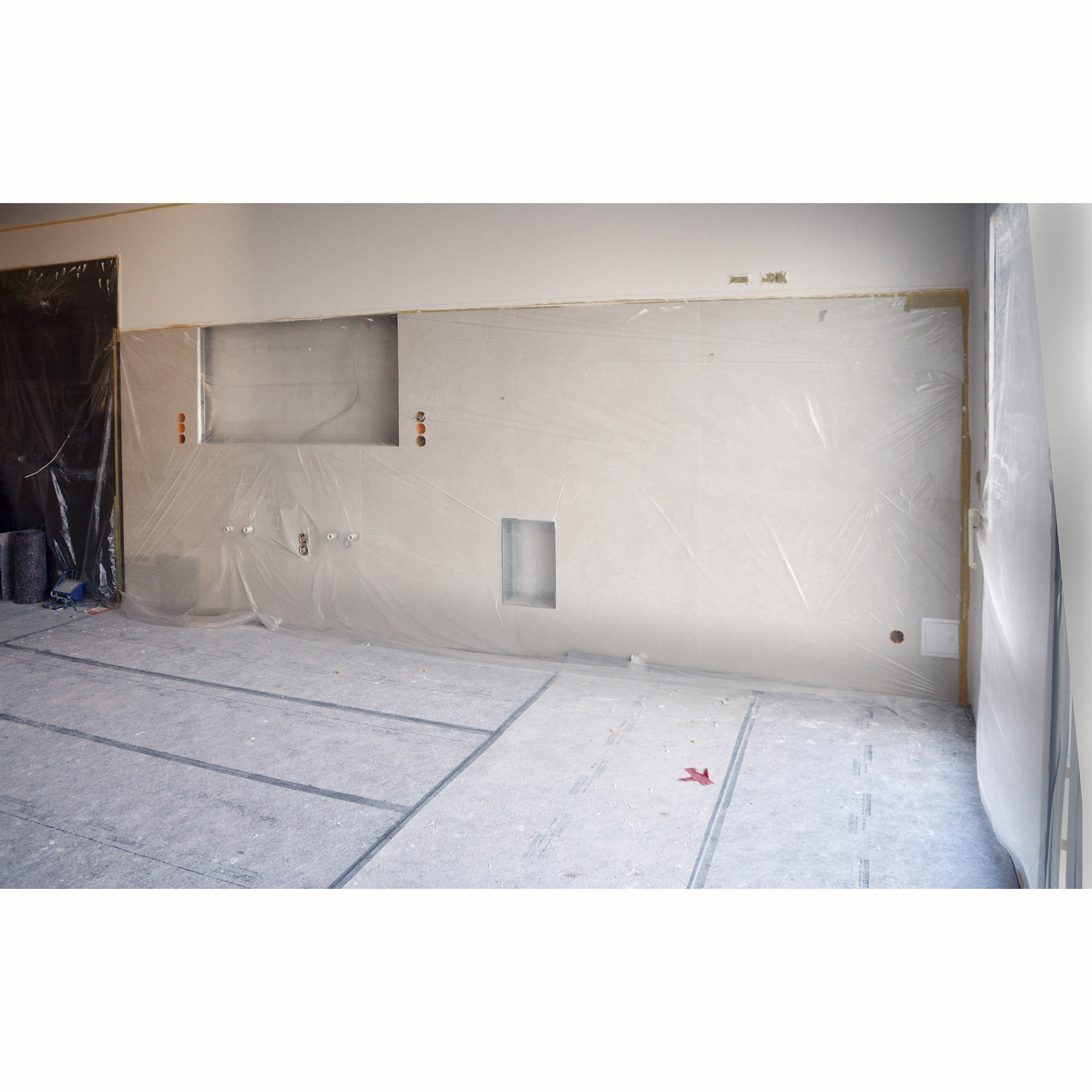 Mit transparenter Staubschutzfolie abgehangene Wand und abgedeckter Boden auf einer Baustelle während Renovierungsarbeiten