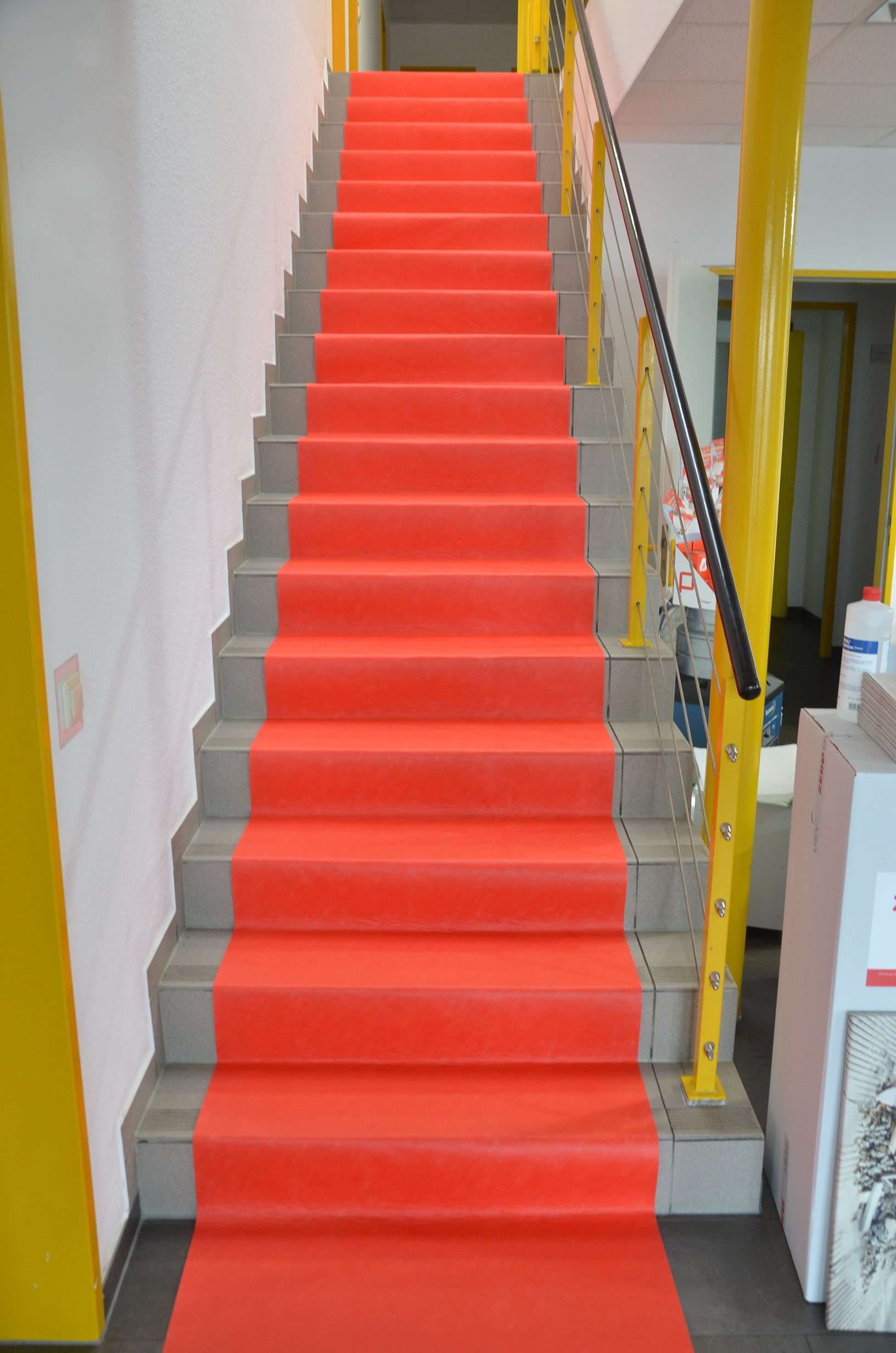 Innenraumtreppe mit leuchtend rotem Treppenschutzläufer als rutschfeste, schützende Abdeckung der Stufen