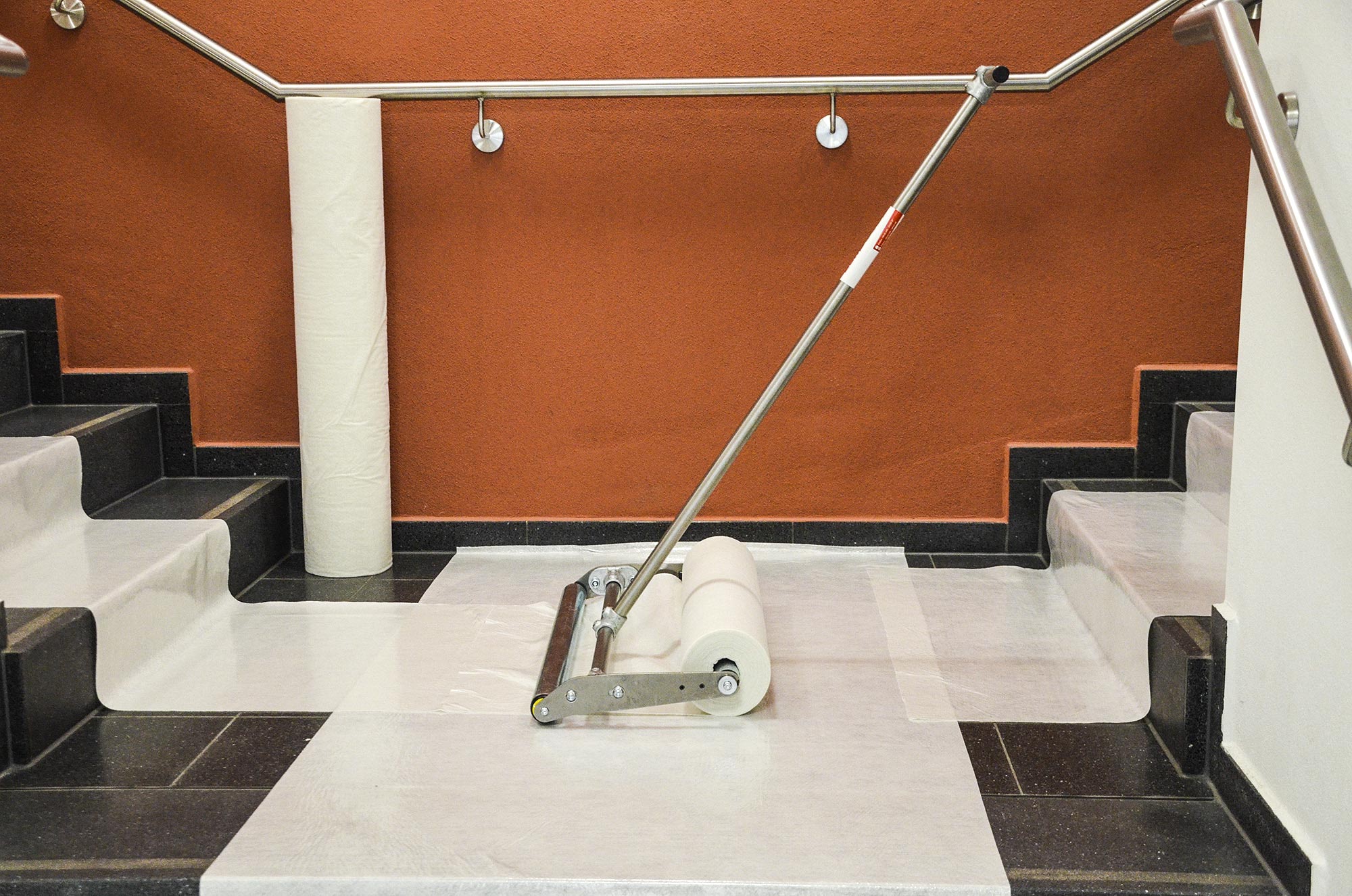 Treppenhaus mit verlegtem Abdeckvlies und Verlegegerät zum schnellen Schutz von Stufen und Boden während Renovierungsarbeiten