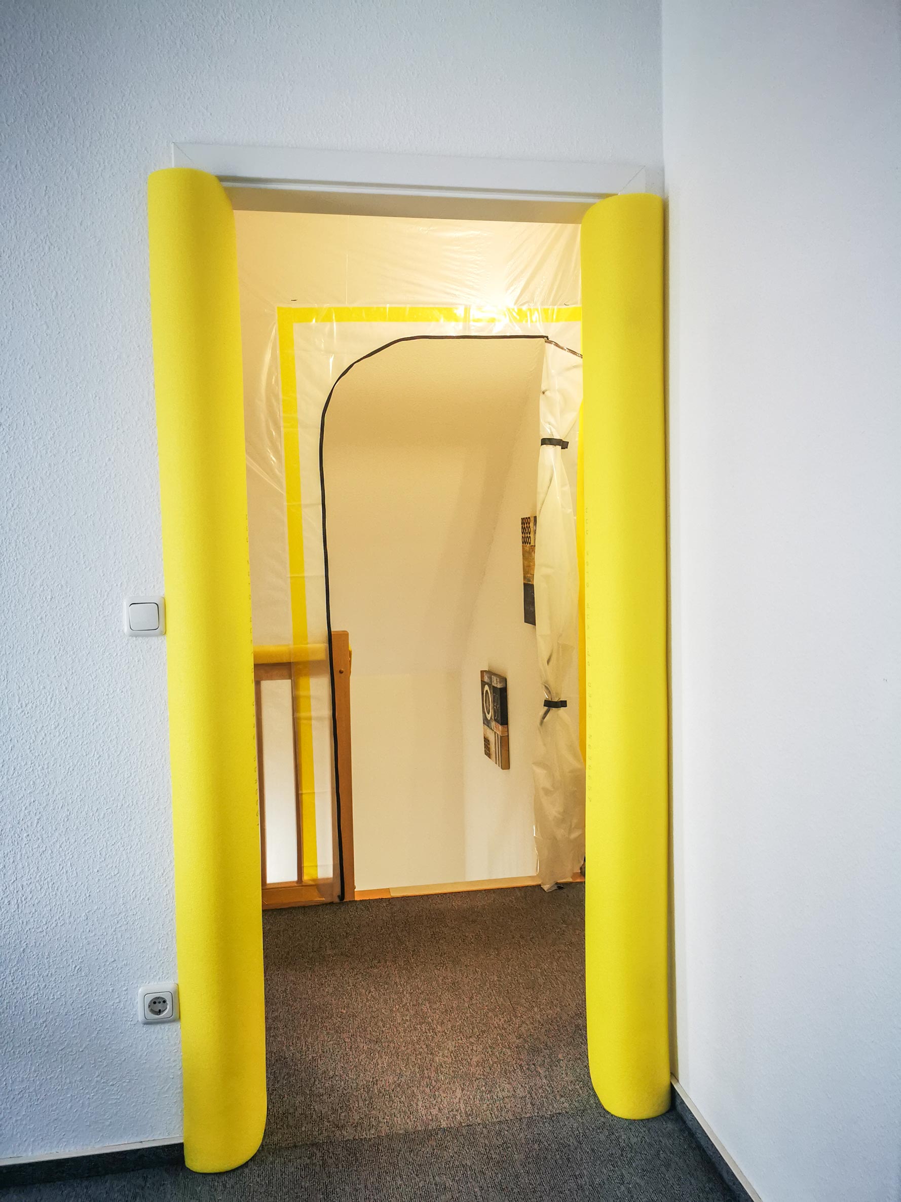 Türzarge mit gelben Schaumstoff-Türschützern als Kantenschutz zum Schutz vor Stößen und Beschädigungen bei Renovierungsarbeiten