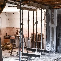 Baustelle in einer Wohnung mit abgestützter Decke, offenen Wänden, Leiter und Baumaterial bei Sanierungsarbeiten