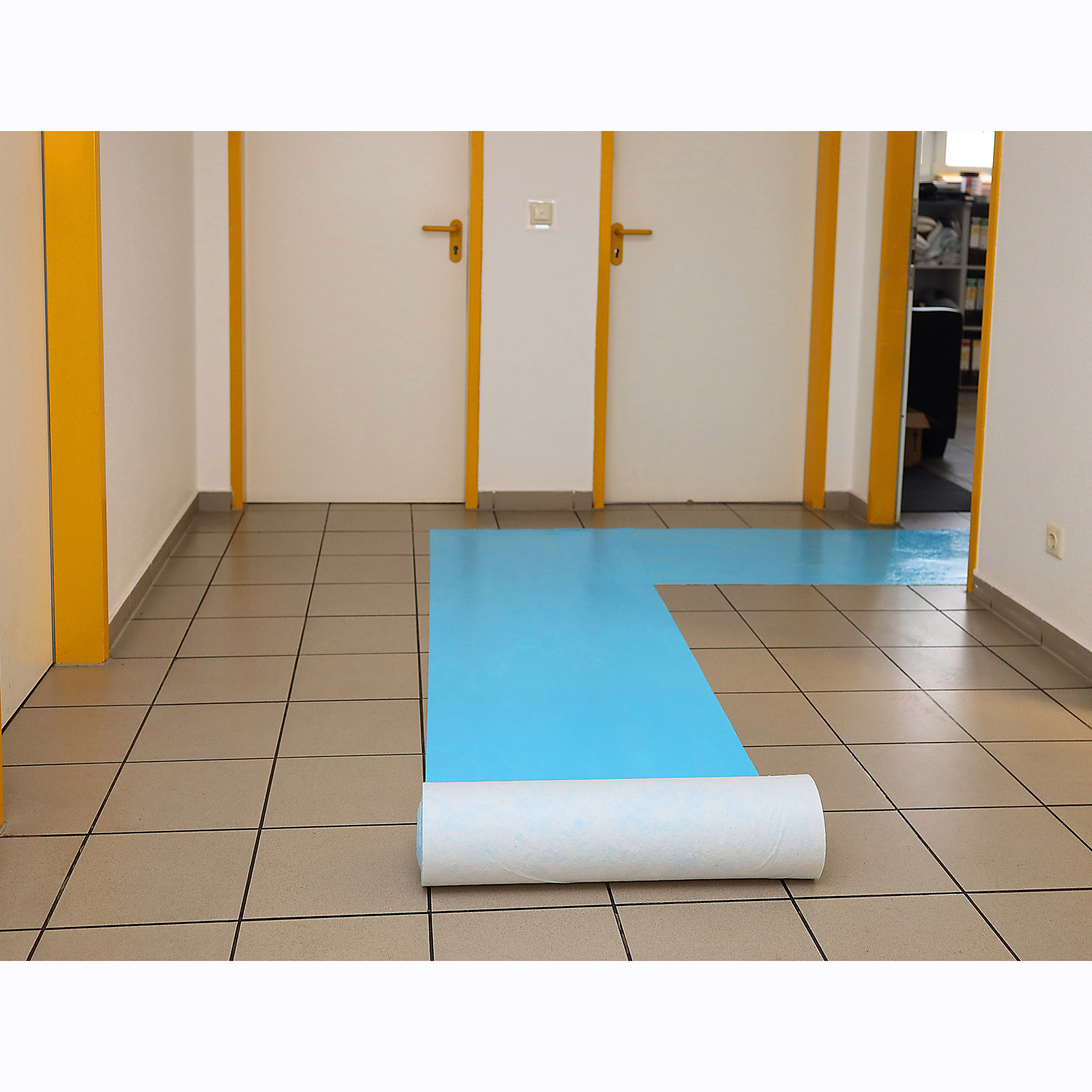 Ausgerollte selbstklebende blaue Schutzfolie als temporäre Bodenabdeckung auf gefliester Flurfläche