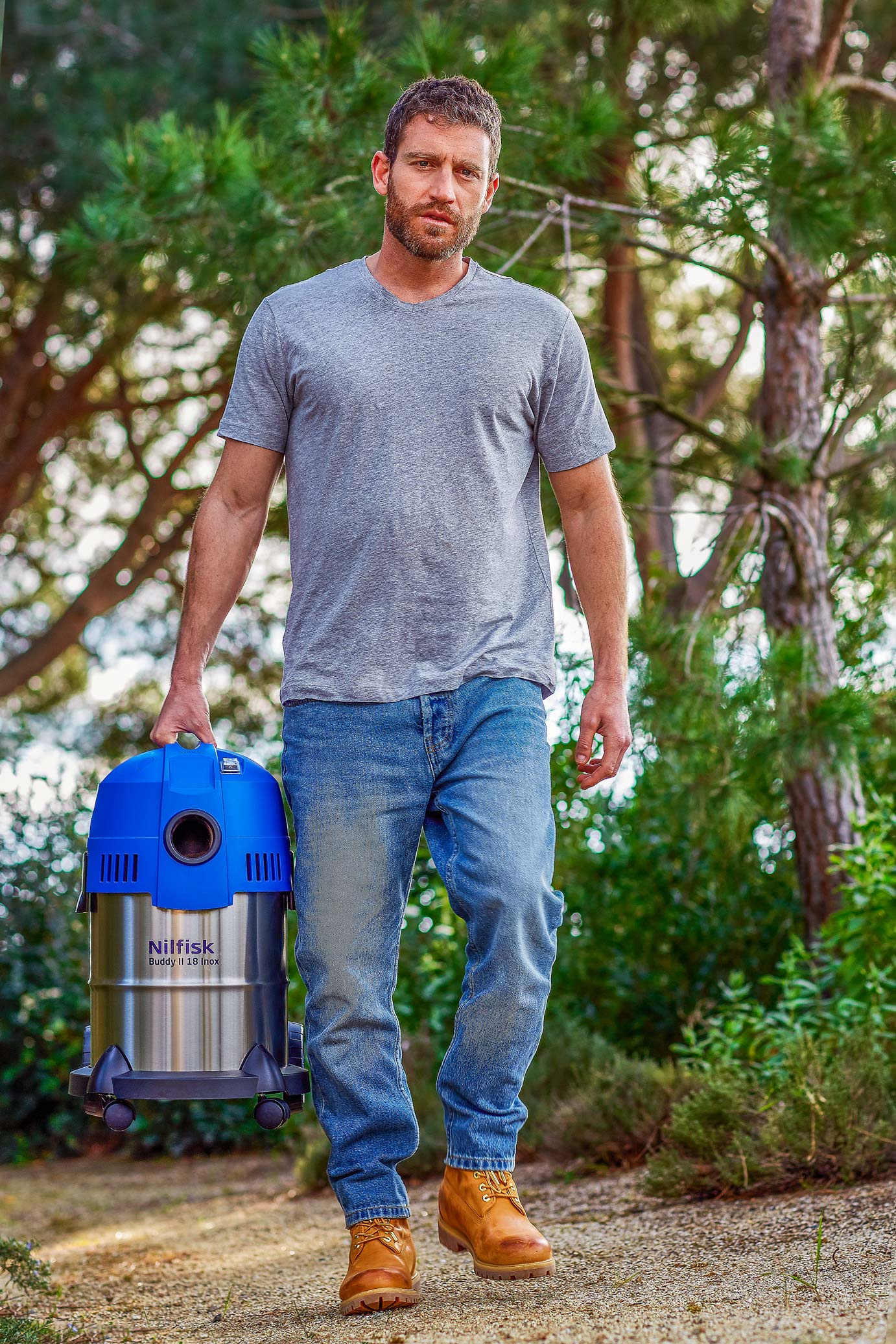 Mann trägt Nilfisk Buddy II 18 Inox Nass- und Trockensauger