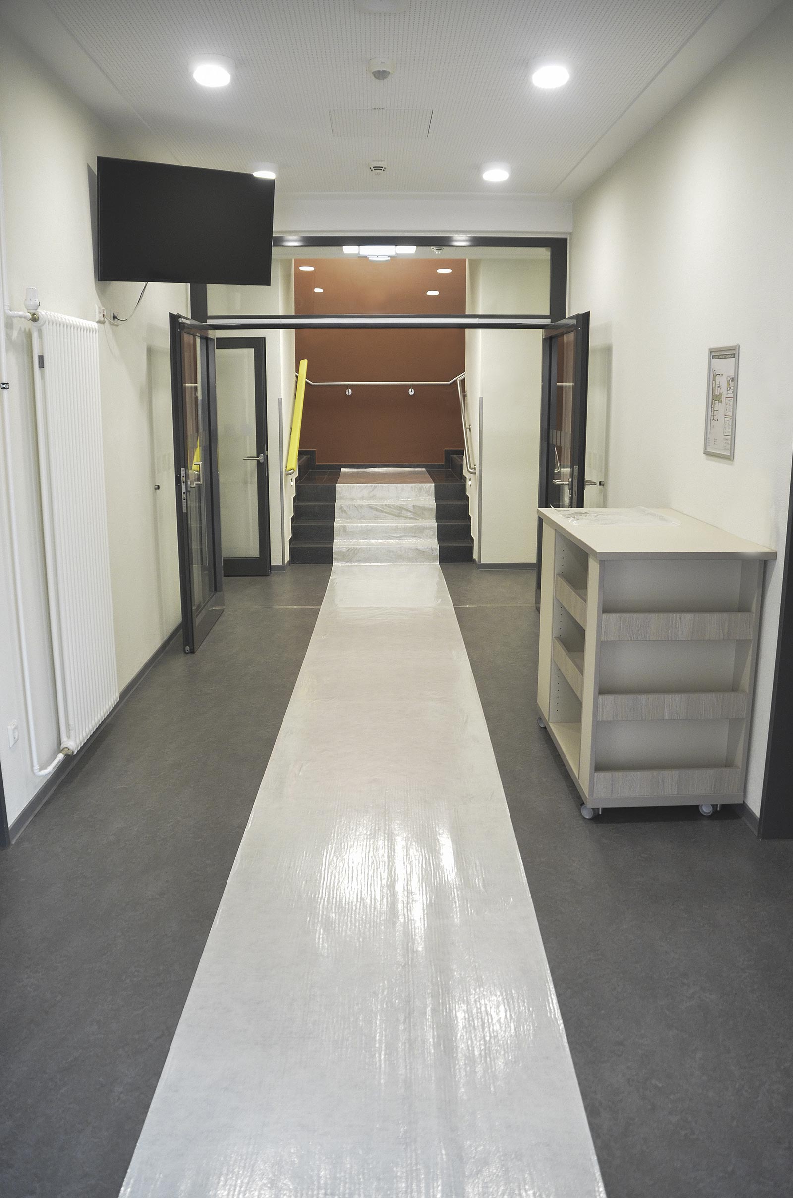 Langer Flur mit selbstklebender Bodenabdeckfolie als Schutzweg über den Boden und die Treppe bei Renovierung