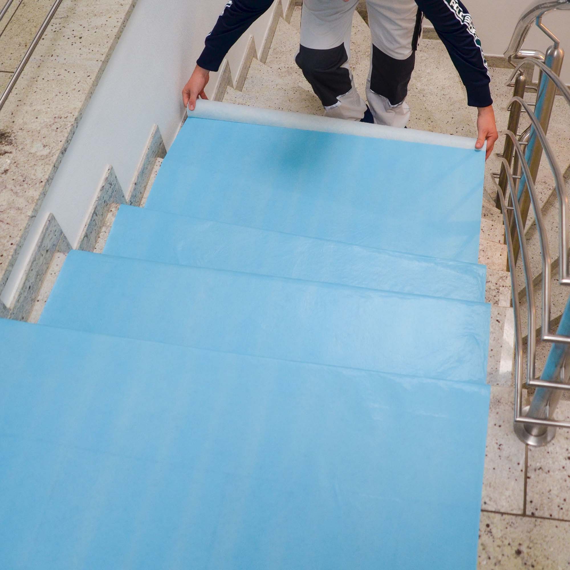 Verlegung von Zero Dust AktivTurbo selbsthaftendem, atmungsaktivem Abdeckvlies 160 g/m² auf einer Steintreppe zum Schutz frisch verlegter Böden vor Schmutz, Feuchtigkeit und Beschädigungen