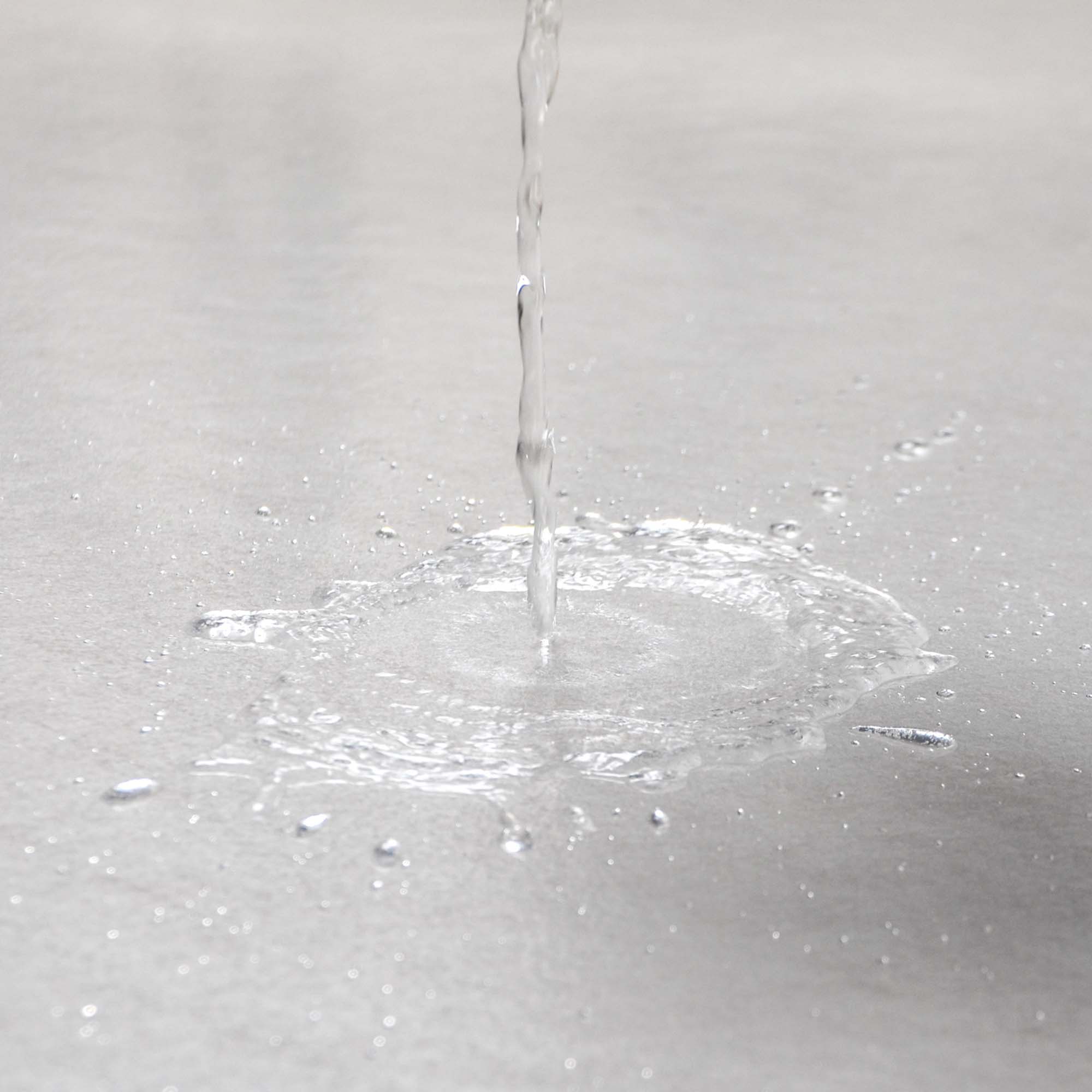 Nahaufnahme des Zero Dust TSV Treppenschutzvlies selbsthaftend 160 g/m² in Weiß, Wasser perlt flüssigkeitsabweisend von der Oberfläche ab