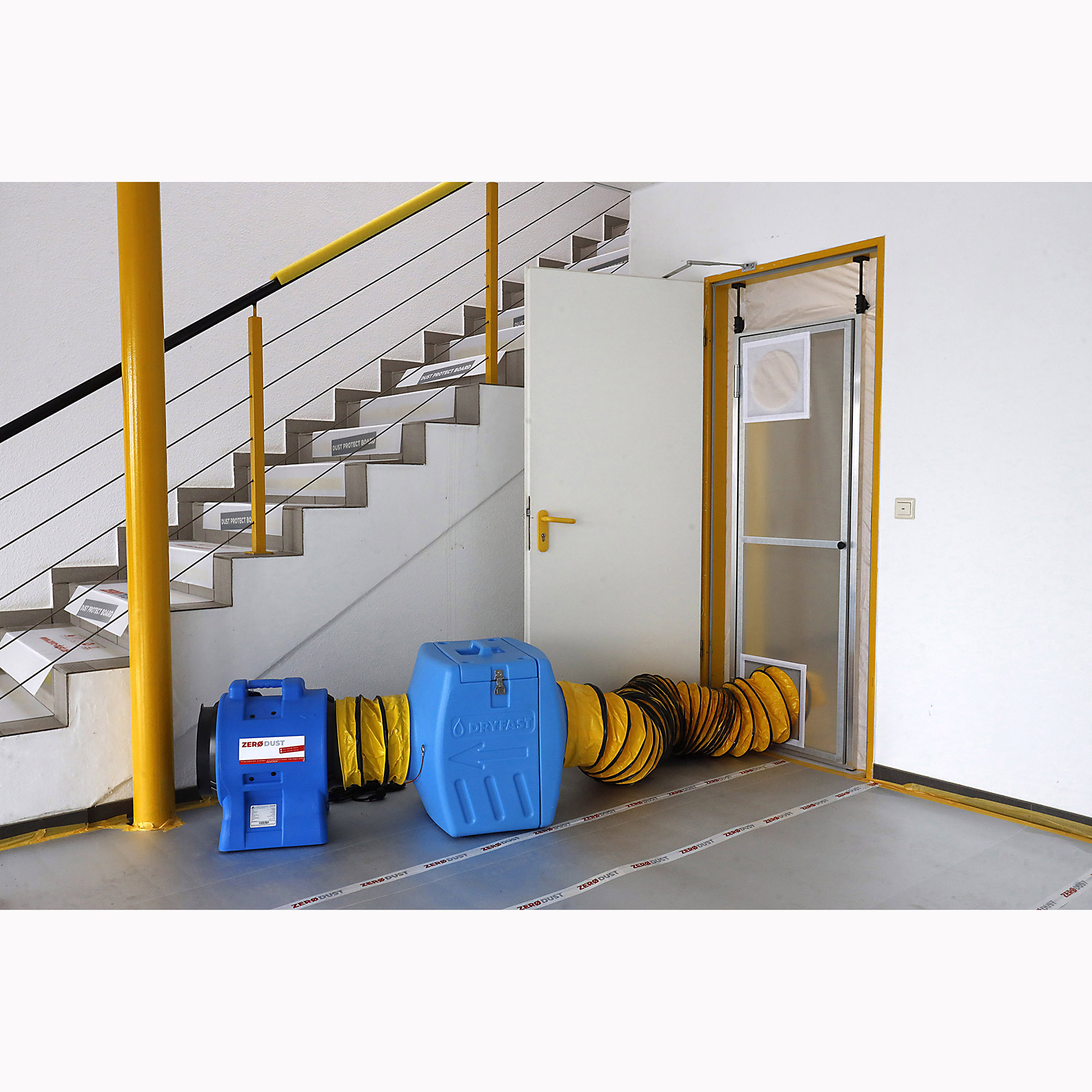 Aufbau einer Staubschutztür mit Rahmen in einer Türöffnung, angeschlossen an ein blaues Unterdruckhaltegerät mit gelbem Luftschlauch zur staubfreien Sanierung im Innenraum