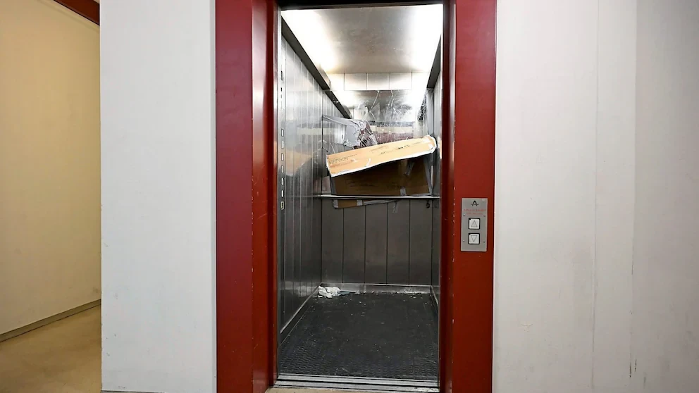 Offener Lastenaufzug mit übergroßem, beschädigtem Karton und Verpackungsmaterial im Inneren