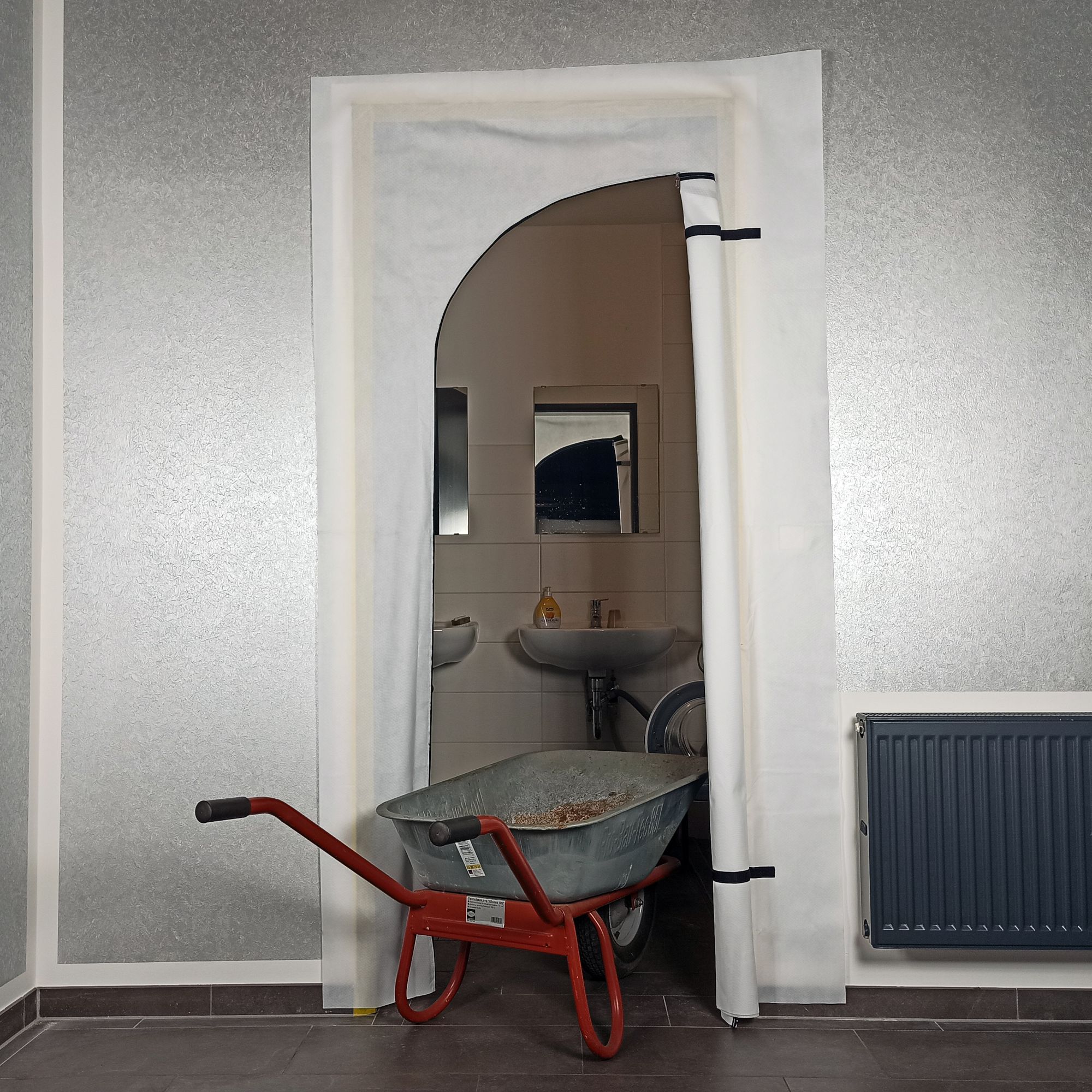 Schwellenlose ZERO DUST Staubschutztür BLITZ 220 × 120 cm im Türeinsatz auf Baustelle, schützt Räume vor Staub bei Renovierung; Aktionspaket mit 25 Stück plus GRATIS-Prämie.